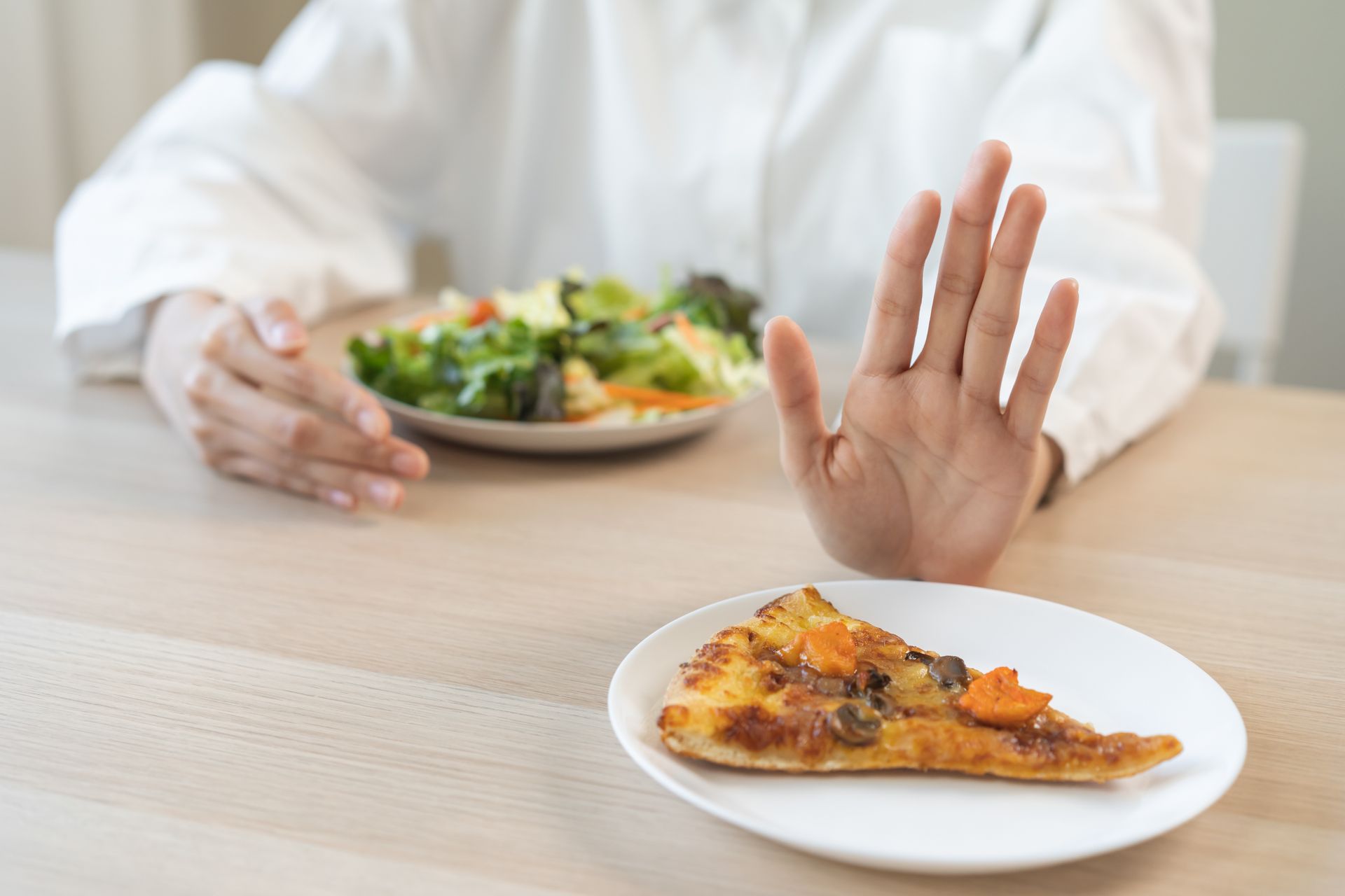 Une personne refuse une part de pizza en faisant un geste de la main.
