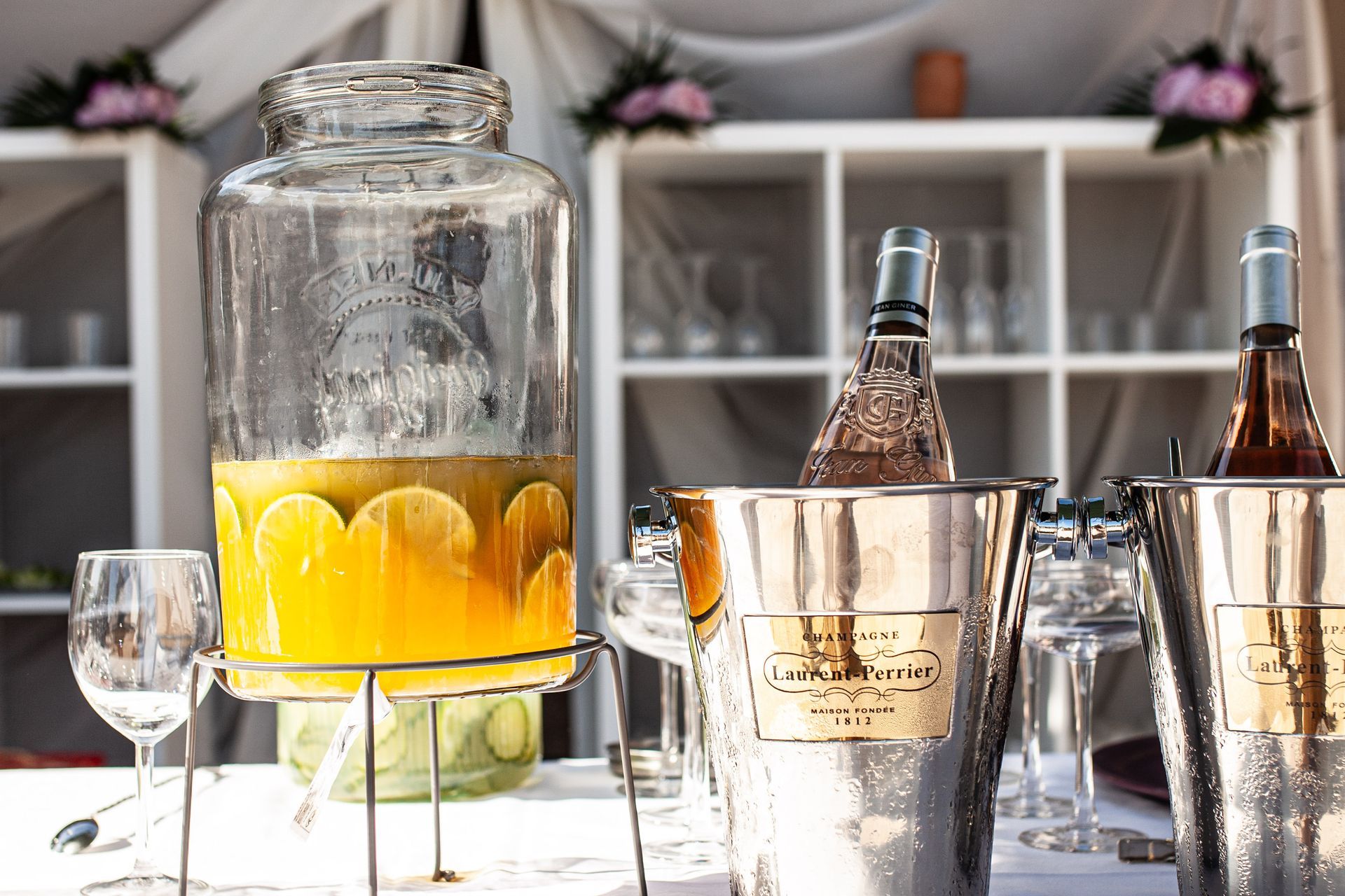 Station de boissons avec distributeur de jus, champagne et vin dans des seaux à glace ; verres devant.