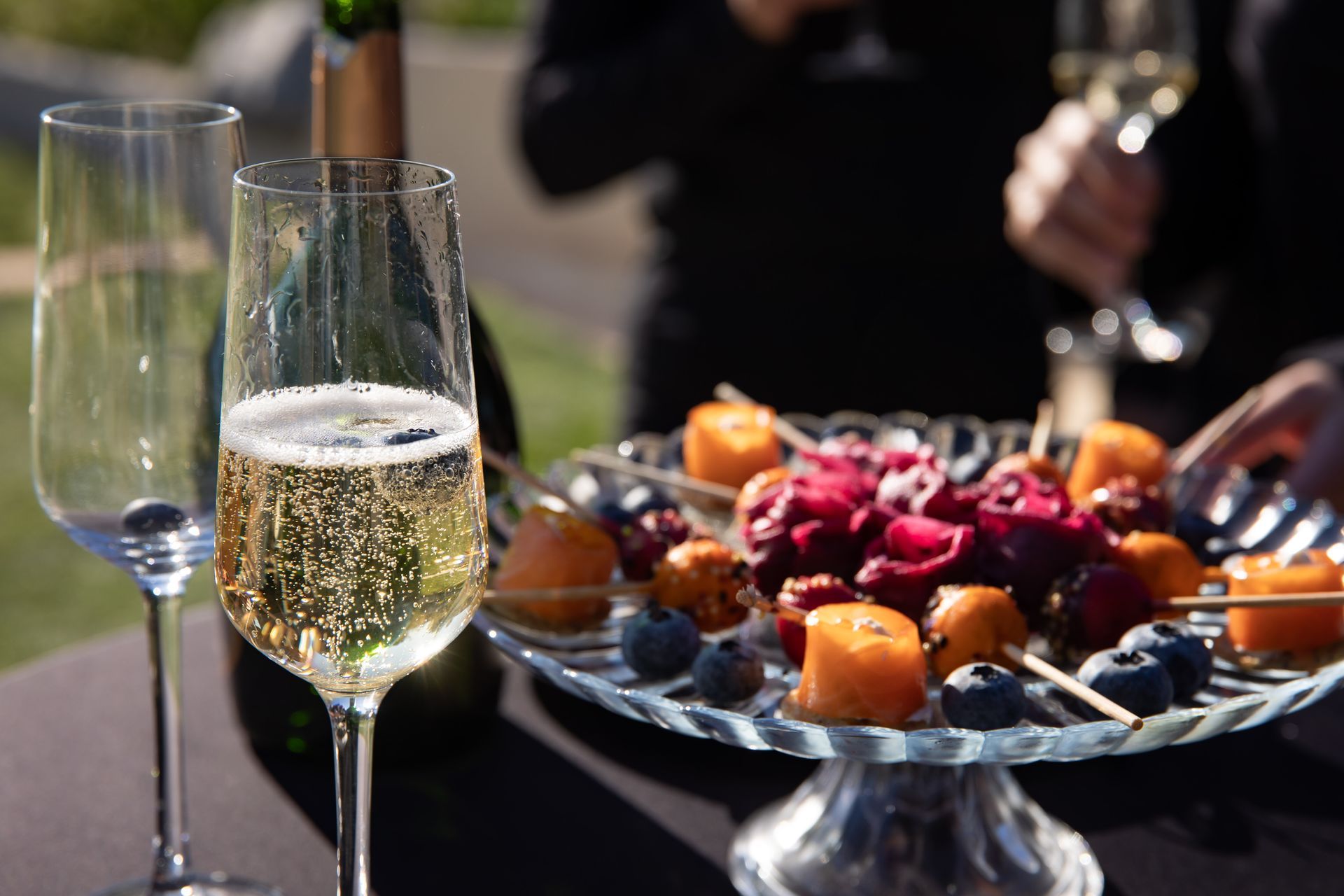 Il y a une assiette de fruits et une coupe de champagne sur la table.