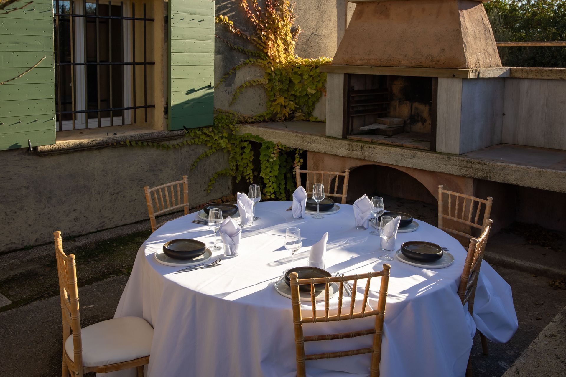 Une table ronde avec une nappe blanche et des chaises devant une cheminée.