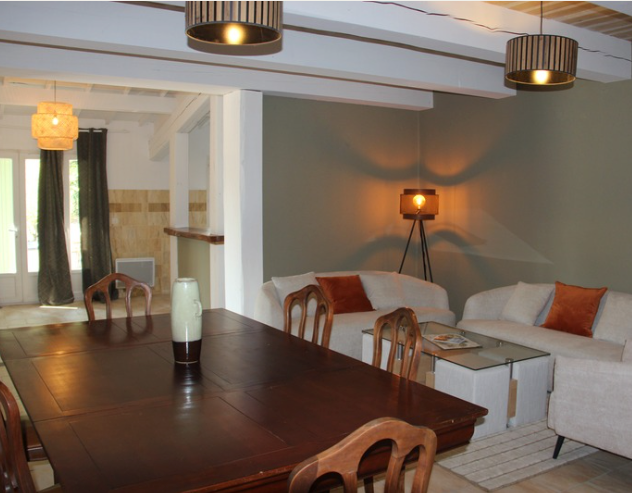 Un salon avec une longue table en bois, des canapés blancs et des suspensions.
