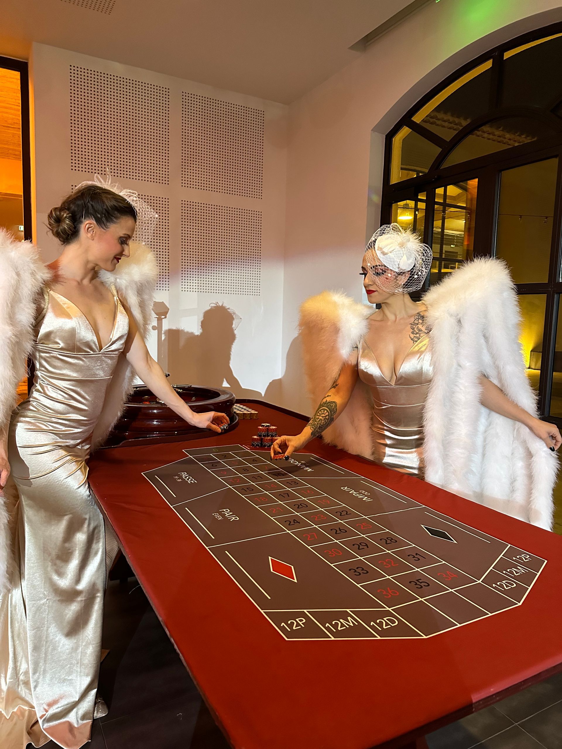 Deux femmes en tenues glamour avec des ailes d'ange à une table de roulette.