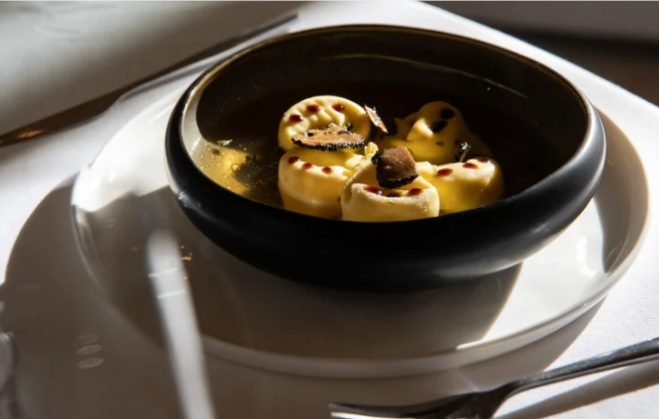 Bol de pâtes aux copeaux de truffe, servi sur une assiette blanche.