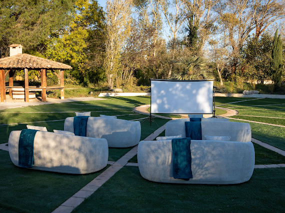 Une rangée de chaises et un écran de projection dans un champ herbeux.