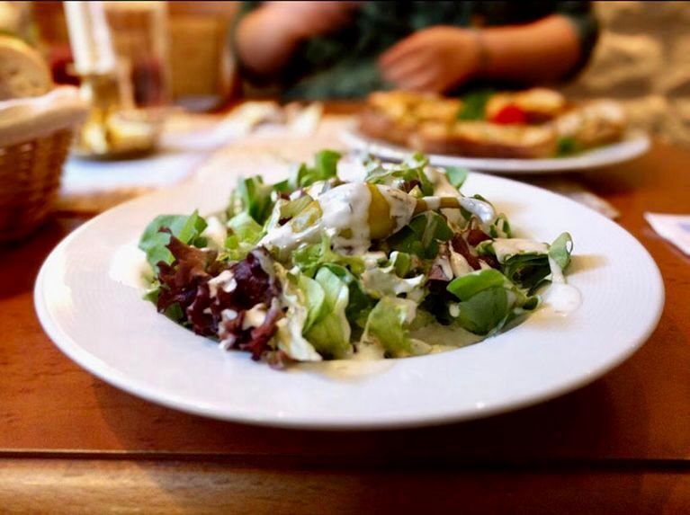 Salat mit weißem Dressing auf einem weißen Teller, auf einem braunen Tisch in einem Restaurant.