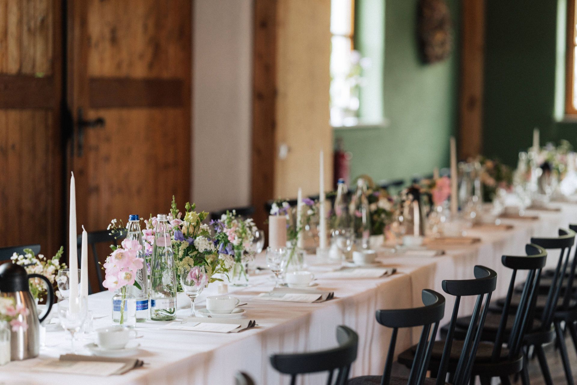 Ein langer, für einen Hochzeitsempfang gedeckter Tisch mit Blumen und Kerzen darauf