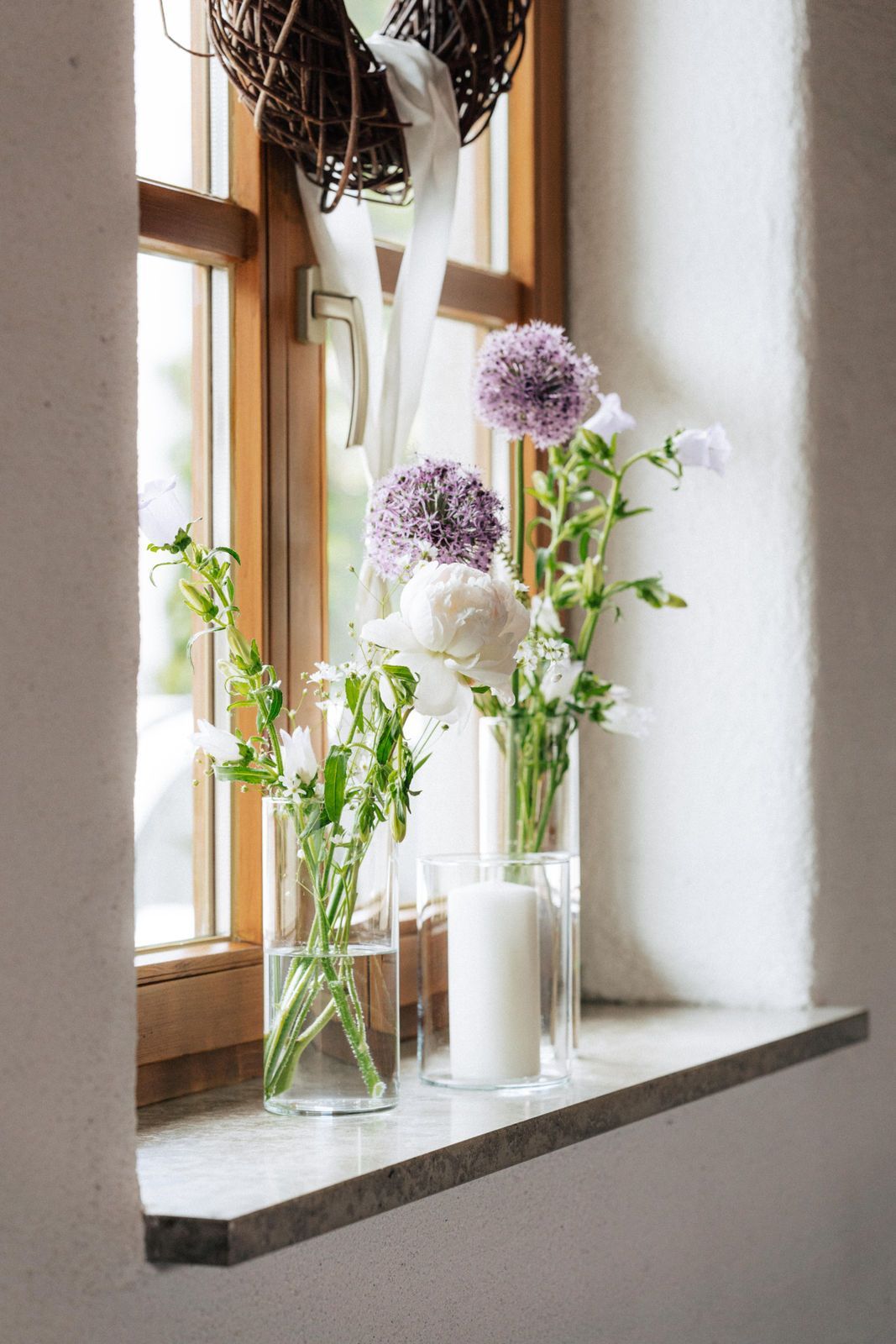 Ein Fensterbrett mit Blumenvasen und einer Kerze darauf