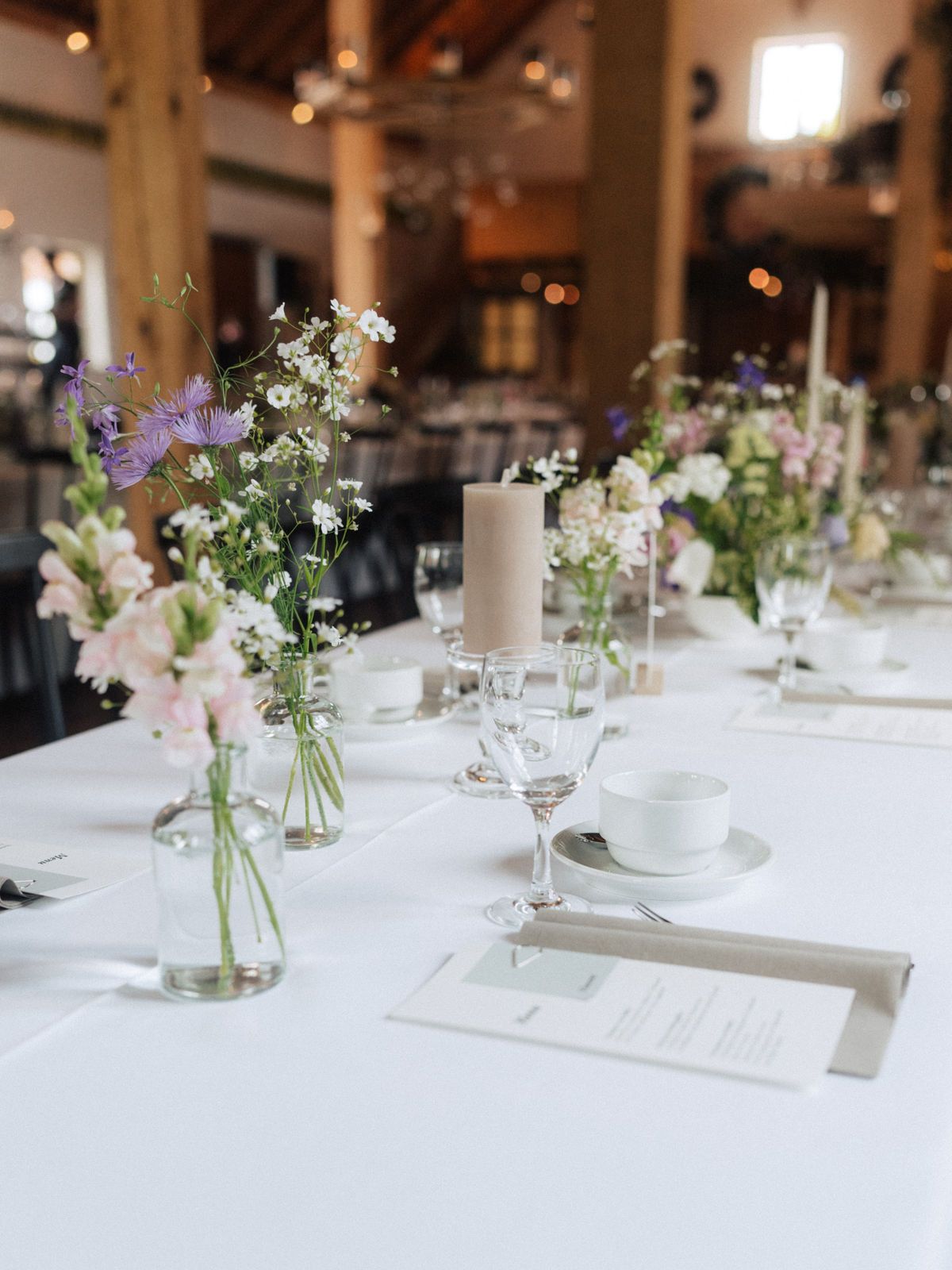 Ein langer Tisch mit Blumen in Vasen und Kerzen darauf