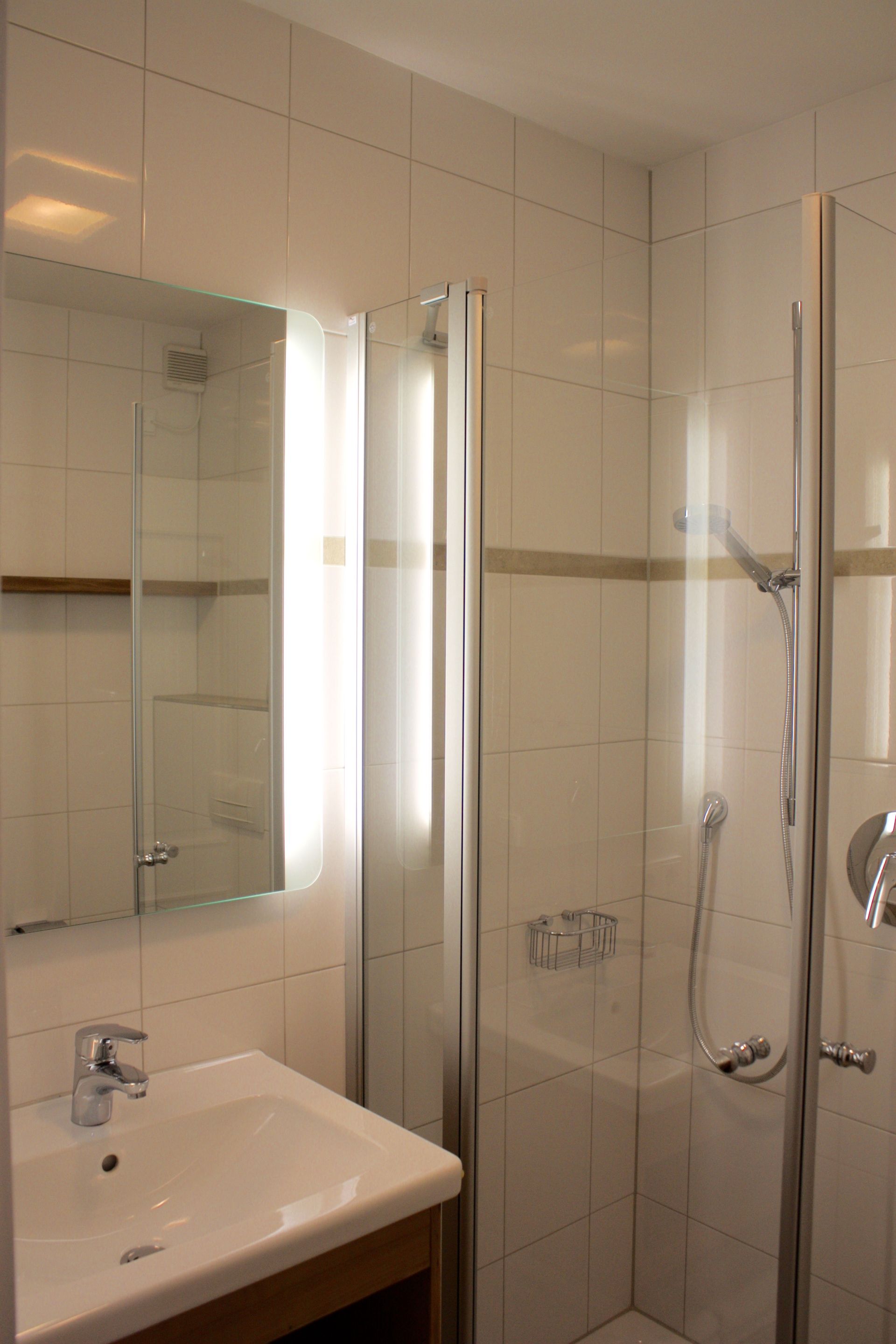 Ein Badezimmer mit Waschbecken, Spiegel und Duschkabine