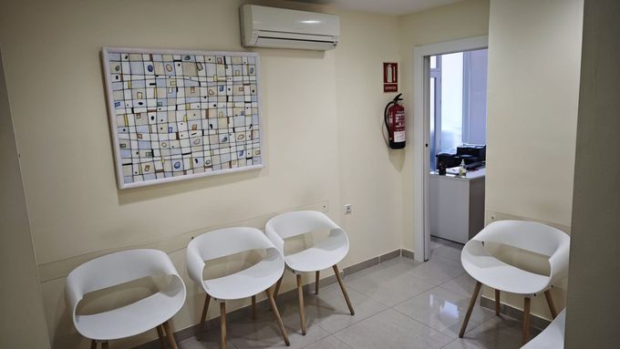 Pequeña sala de espera con sillas blancas, suelo de baldosas