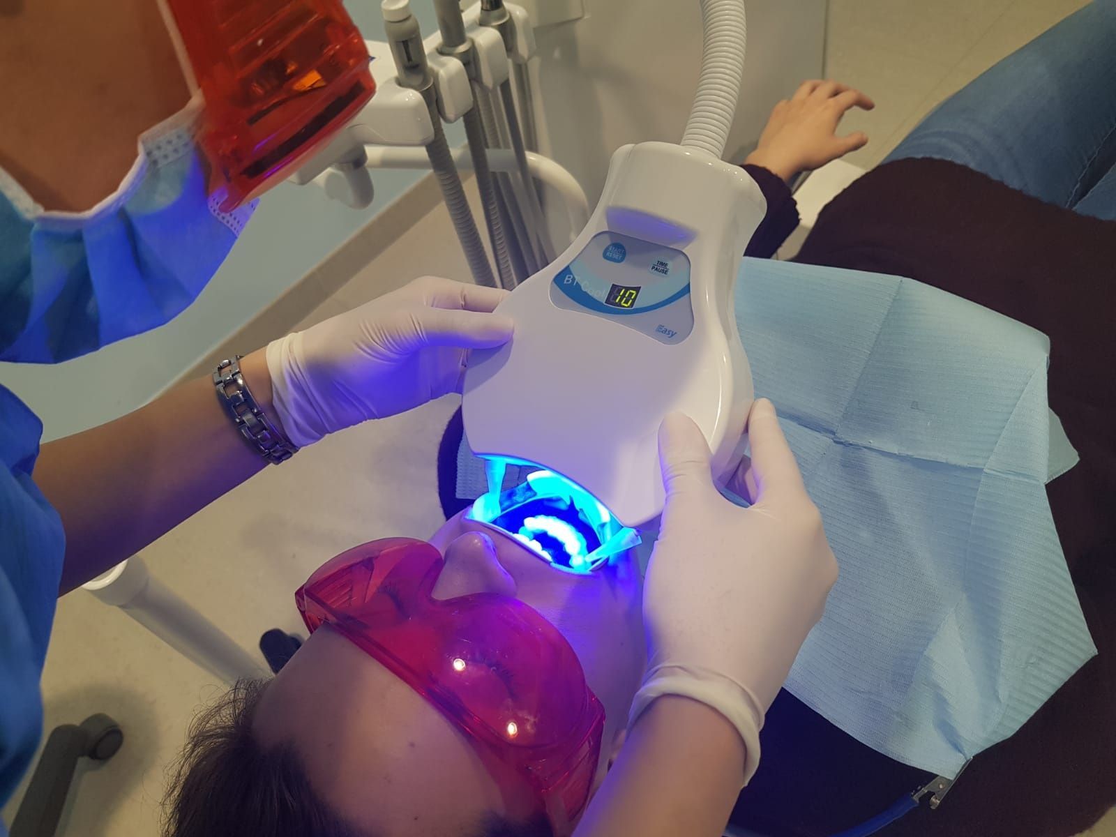 Odontólogo examinando la boca de un paciente con un espejo dental y la mano enguantada.