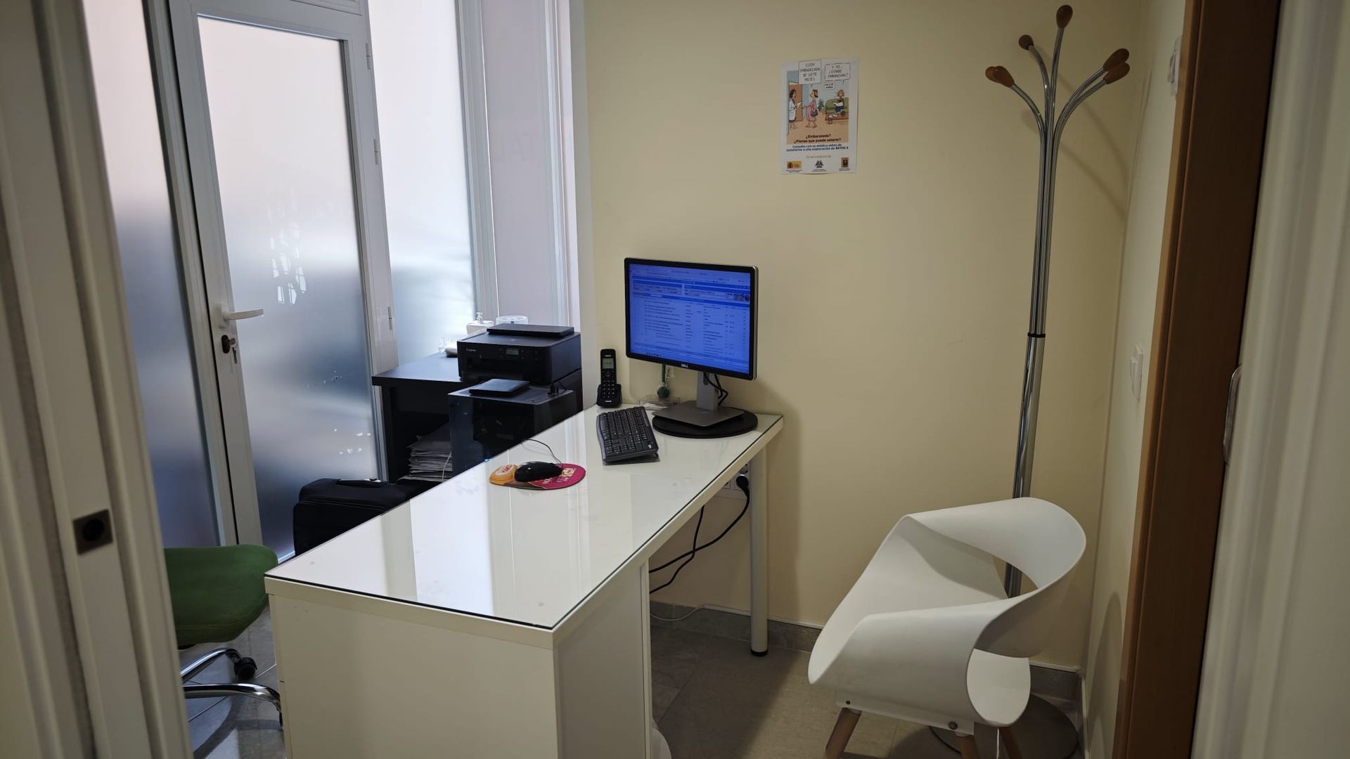 Pequeña oficina con un escritorio blanco, un monitor de ordenador