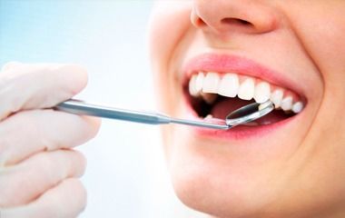 Odontólogo examinando la boca de un paciente con un espejo dental y la mano enguantada.