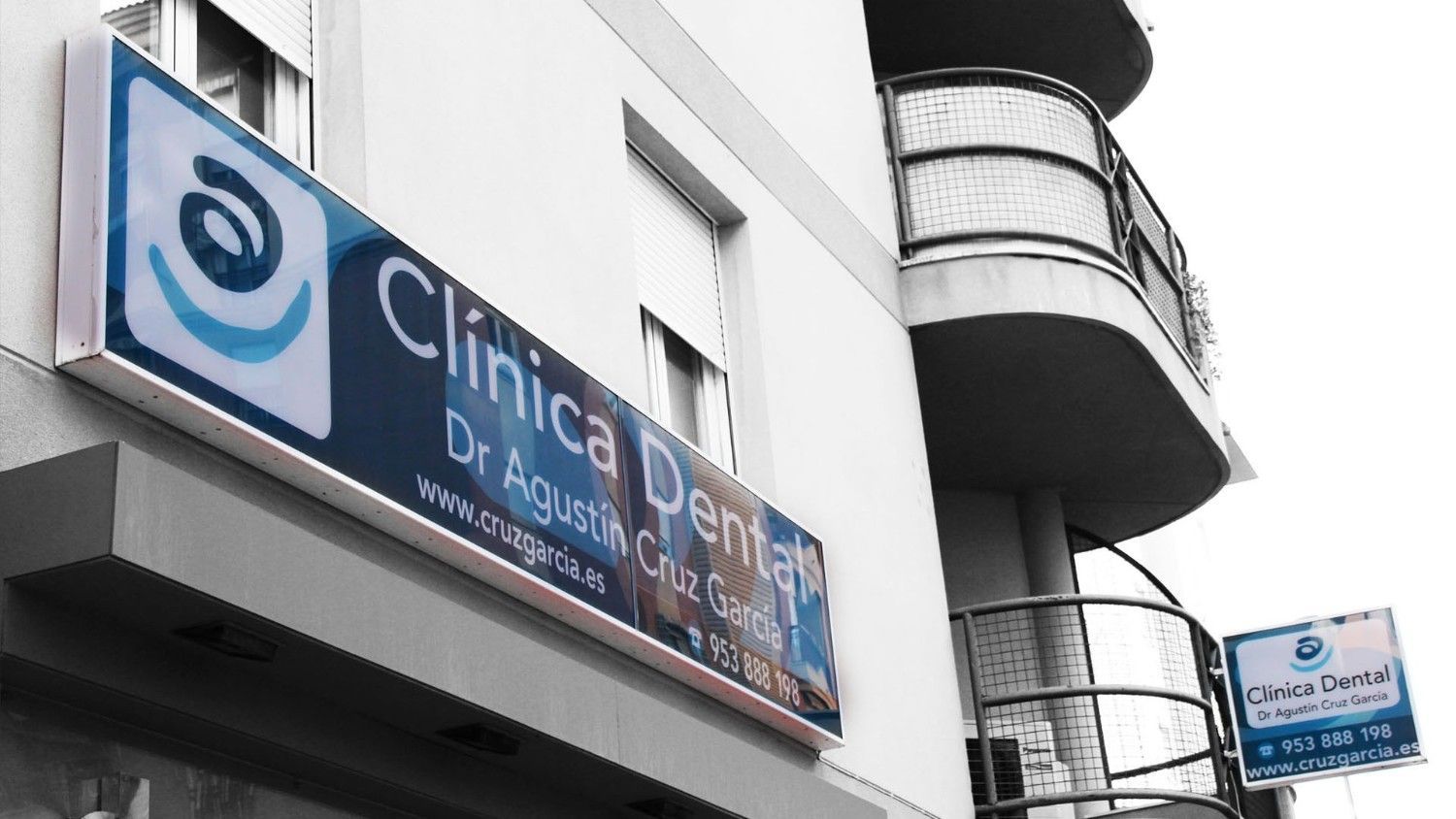 Letrero azul y blanco de Clínica de Ojos en un edificio blanco con balcones.