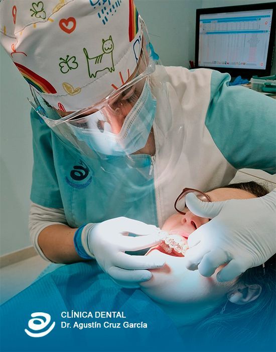 Consultorio dental moderno con sillón azul, instrumental y monitor montado en la pared que muestra un logotipo.