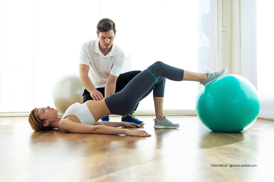 Mitarbeiter der Validus Physio GmbH bei der Durchführung von Rückenübungen mit einer Patientin mit Hilfe eines Gymnastikballs