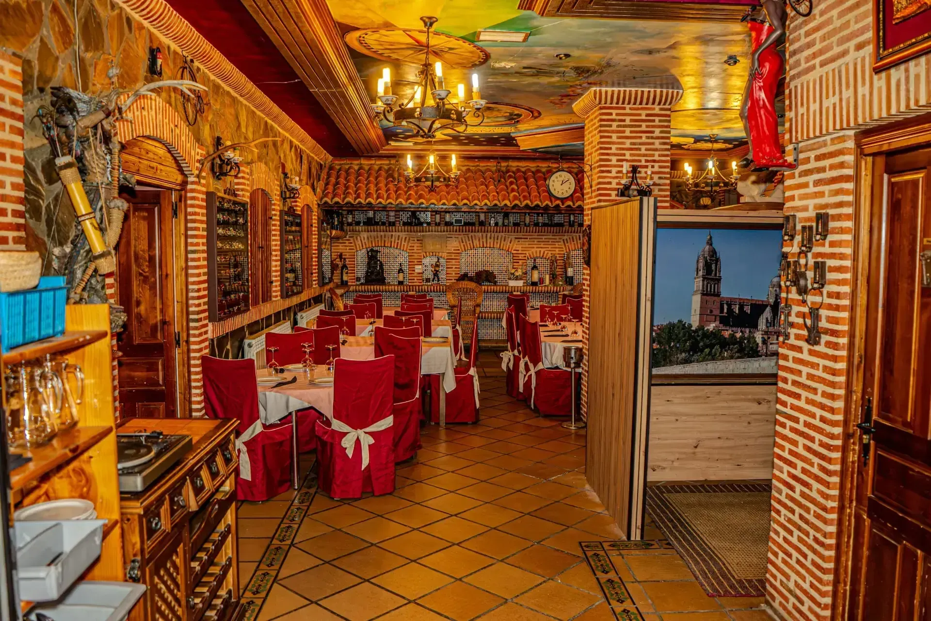 Acogedor restaurante con paredes de ladrillo, manteles rojos, iluminación cálida y suelos de baldosas.