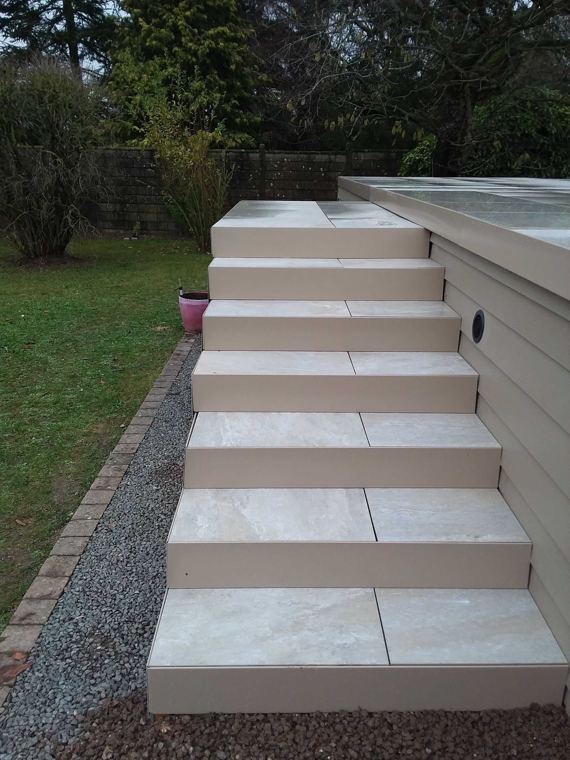 Des escaliers extérieurs beiges qui mènent à une terrasse.