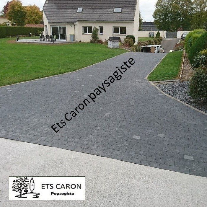 Allée pavée grise à bordure incurvée menant à une maison et une pelouse ; filigrane ETS Caron Paysagiste.