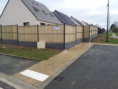 Une clôture en grillage avec lames de bois.