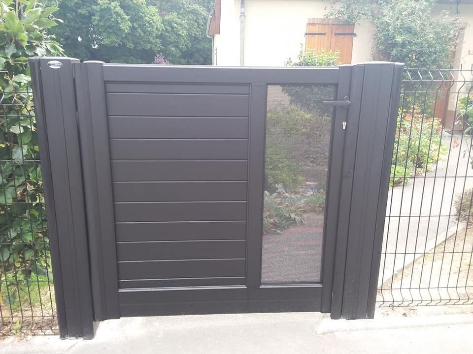 Portail moderne en métal noir avec panneau latéral assorti et étroite section vitrée, donnant sur une allée.