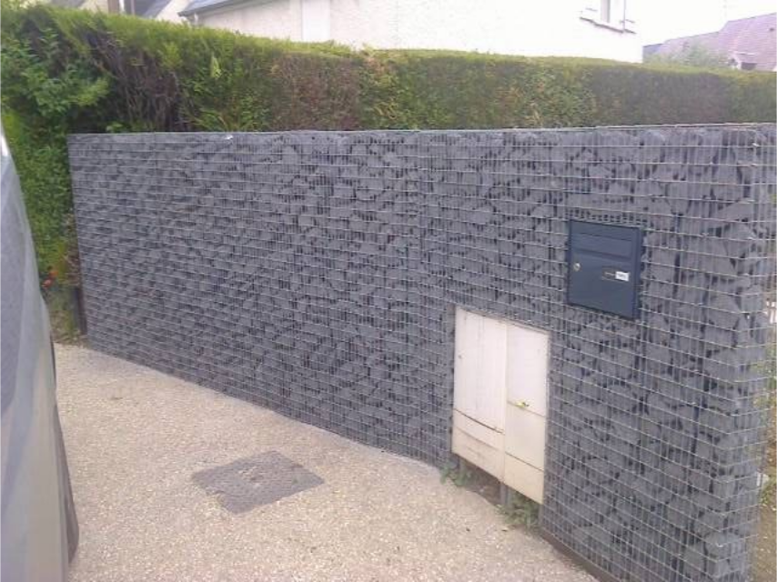 Coin de rue résidentielle avec mur blanc, clôture noire, camionnette garée et panneau de signalisation.