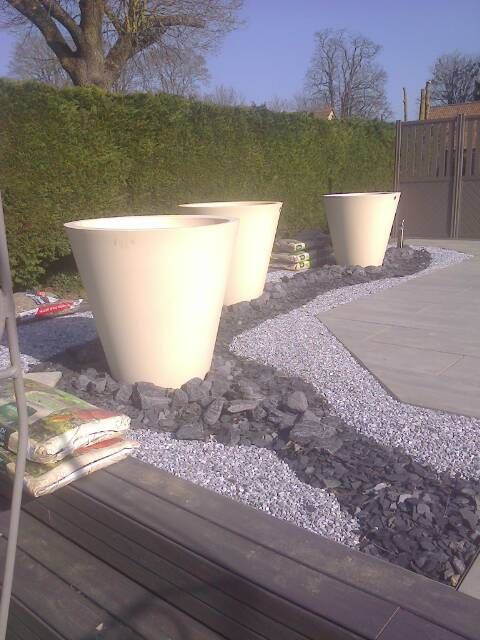 Des pots de fleurs blancs sur une terrasse.