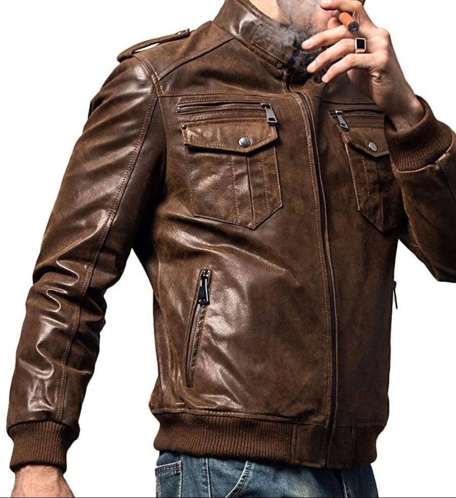 Hombre con chaqueta de cuero marrón fumando, con las manos cerca de la cara. La chaqueta tiene bolsillos y cremallera.