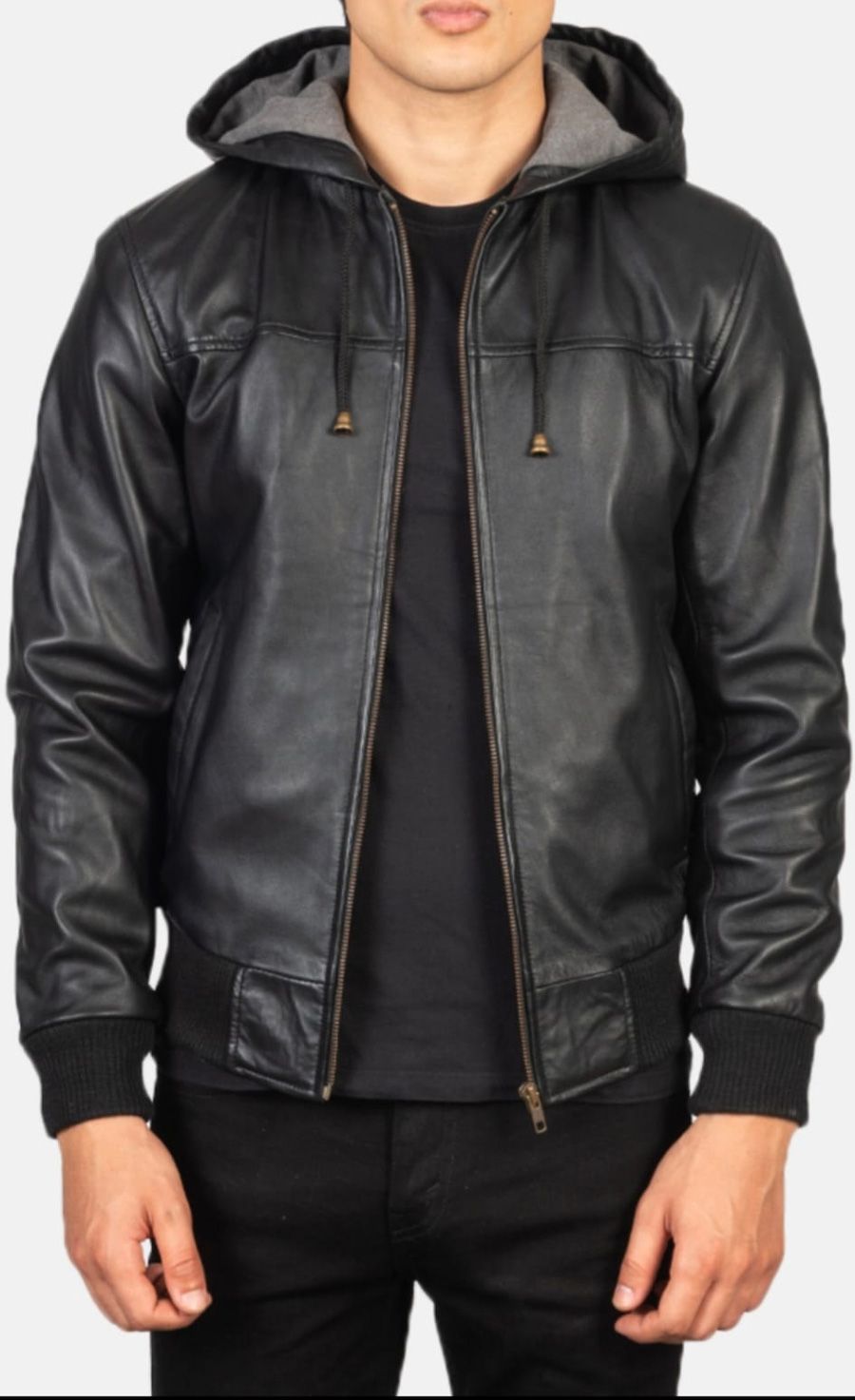 Hombre con chaqueta de cuero negra con capucha, cremallera y de pie.