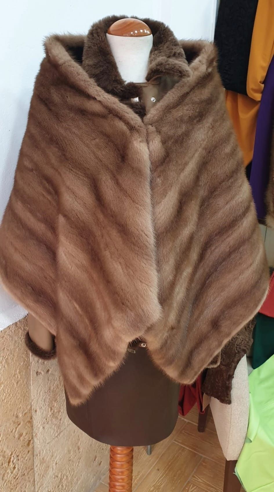 Capa de piel marrón con capucha sobre un maniquí.