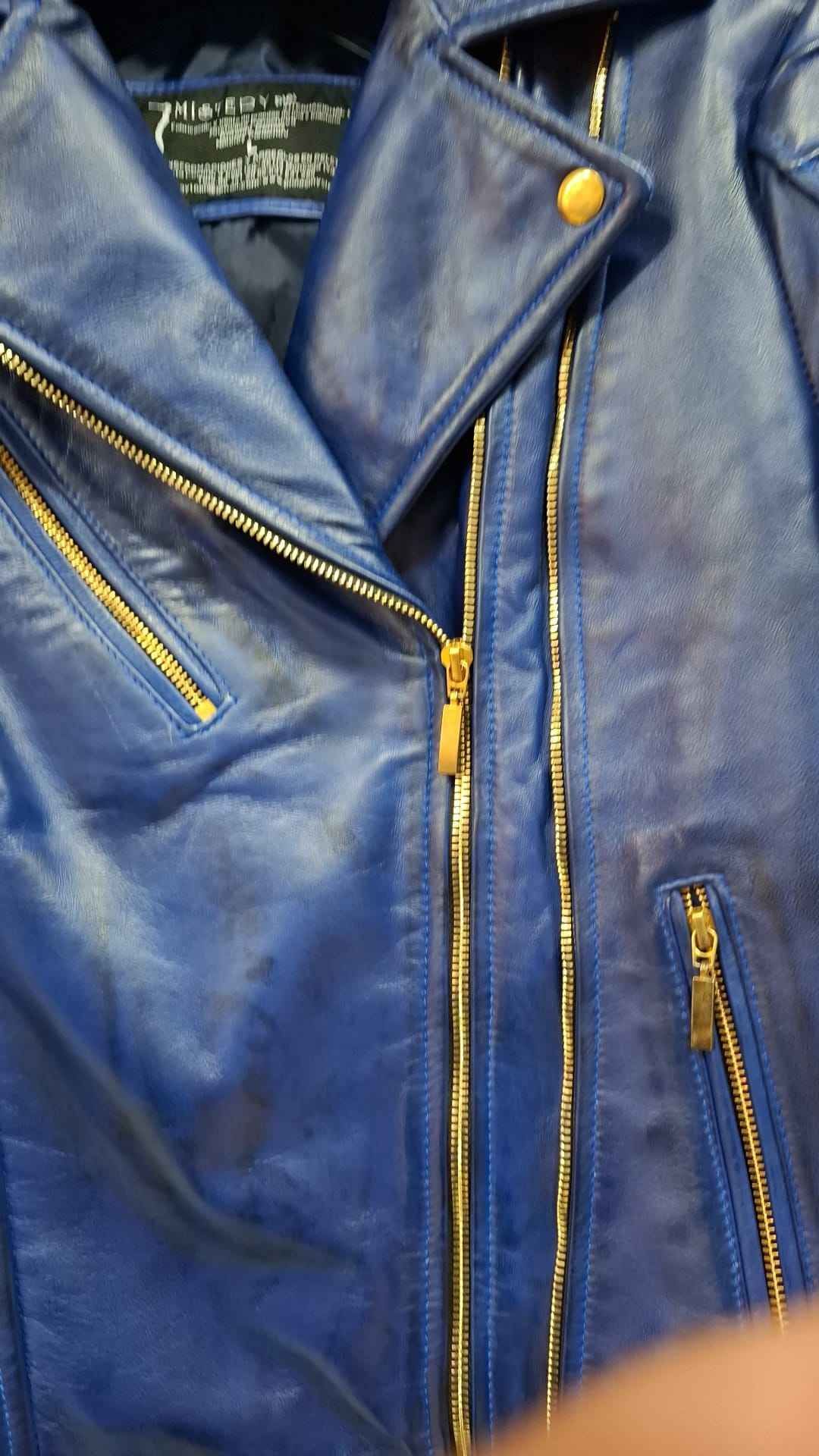 Chaqueta de cuero azul con cremalleras y herrajes dorados.