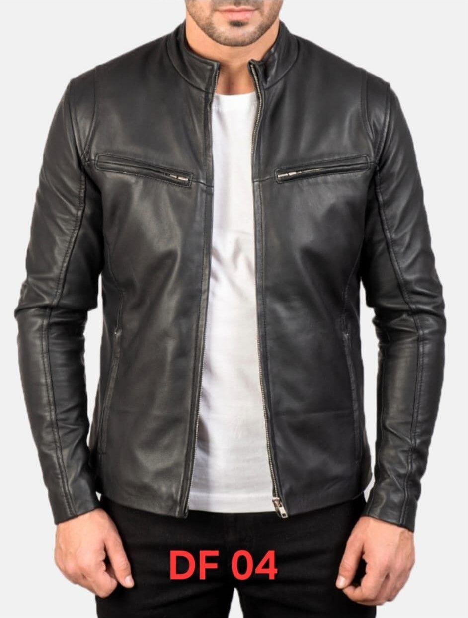 Hombre con chaqueta de cuero negra sobre camisa blanca, de pie en el interior.