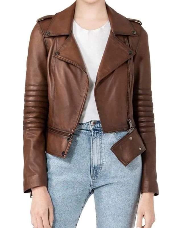 Mujer con una chaqueta de cuero marrón estilo motera sobre una blusa blanca y vaqueros azules.