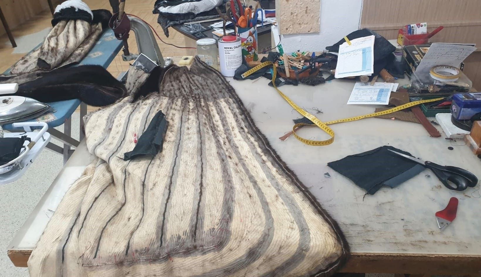 Una mesa de costura con trozos de tela, tijeras y una cinta métrica.