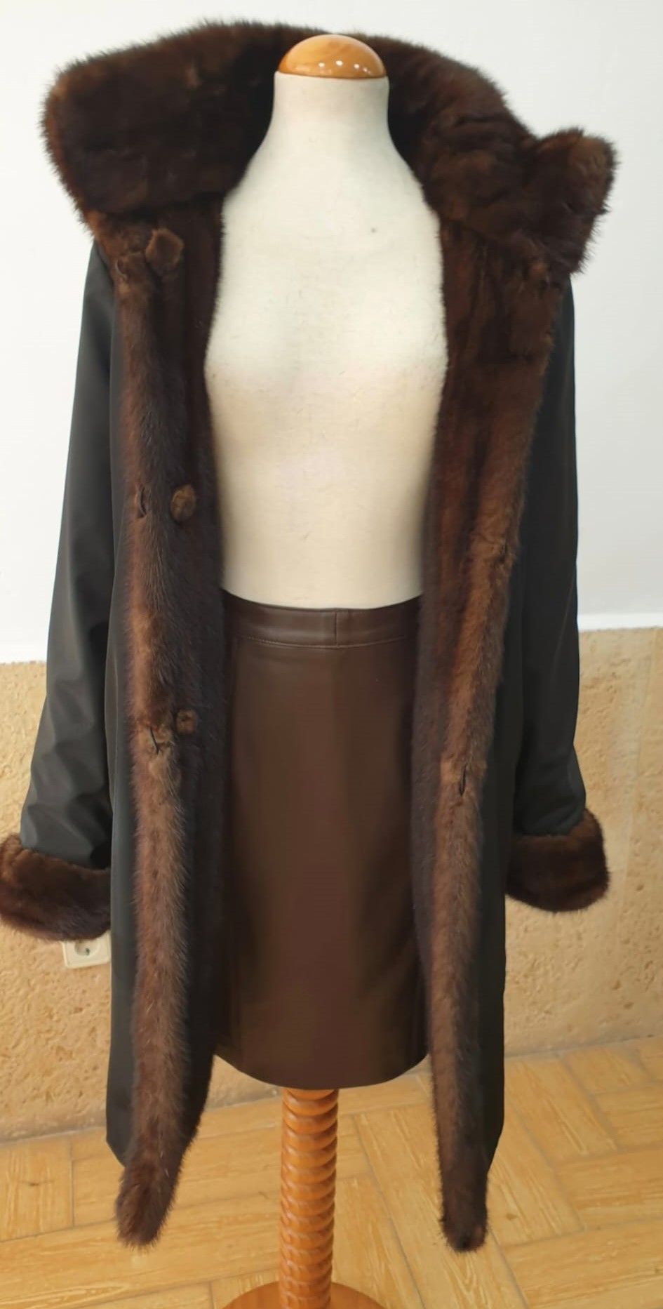 Abrigo negro con ribete de piel marrón sobre un maniquí.