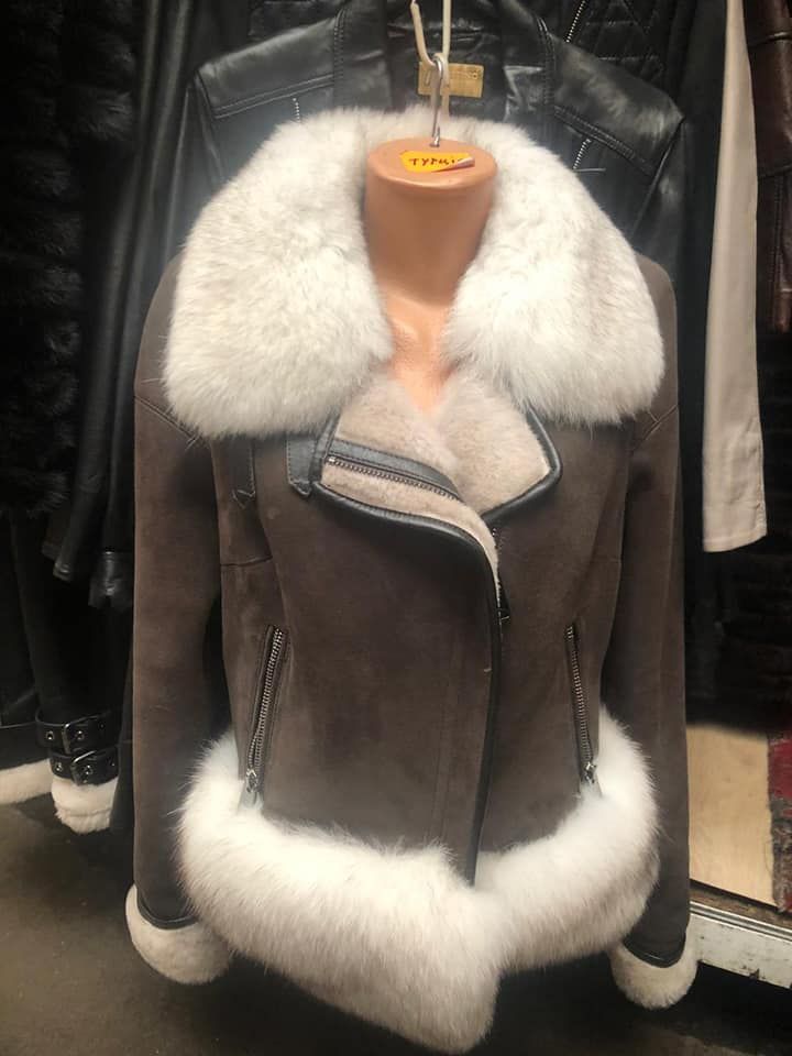 Chaqueta de ante marrón con cuello, puños y forro de piel blanca sobre un maniquí.