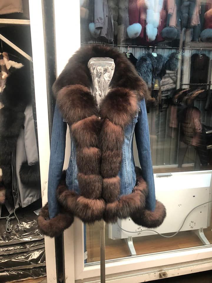 Una chaqueta vaquera azul con ribete de piel marrón en un maniquí dentro de un escaparate.
