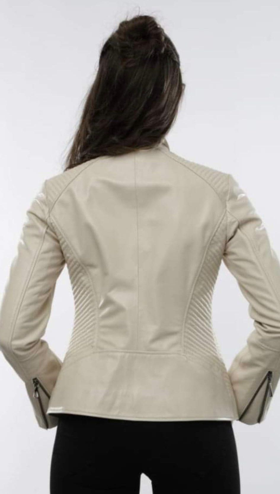 Mujer que lleva una chaqueta de cuero beige desde atrás, con las manos en las caderas y sobre un fondo blanco.