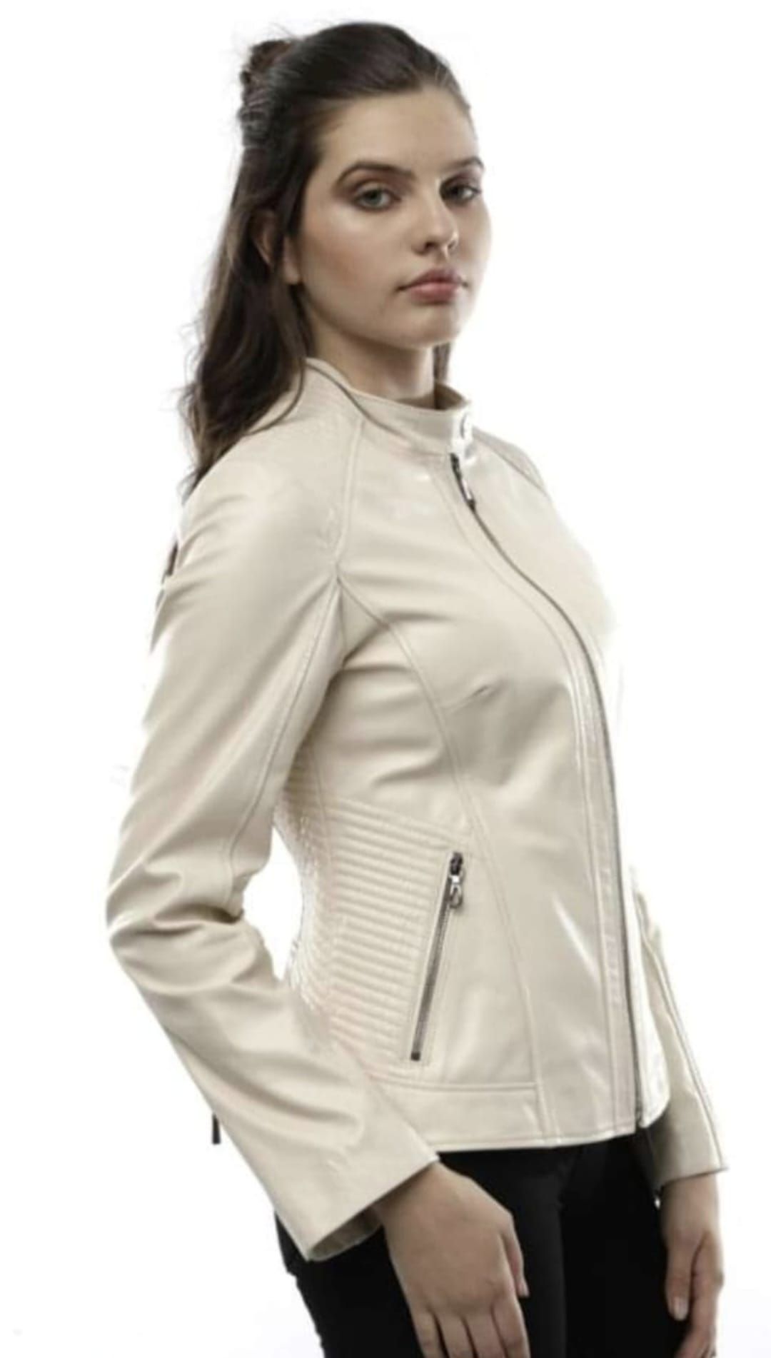 Mujer con una chaqueta de cuero beige, posando sobre un fondo blanco, mirando ligeramente hacia un lado.