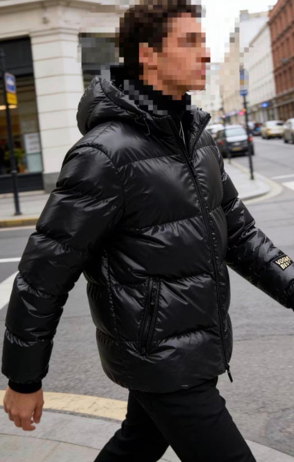 Hombre con chaqueta negra y cuello alto caminando por la calle de la ciudad.