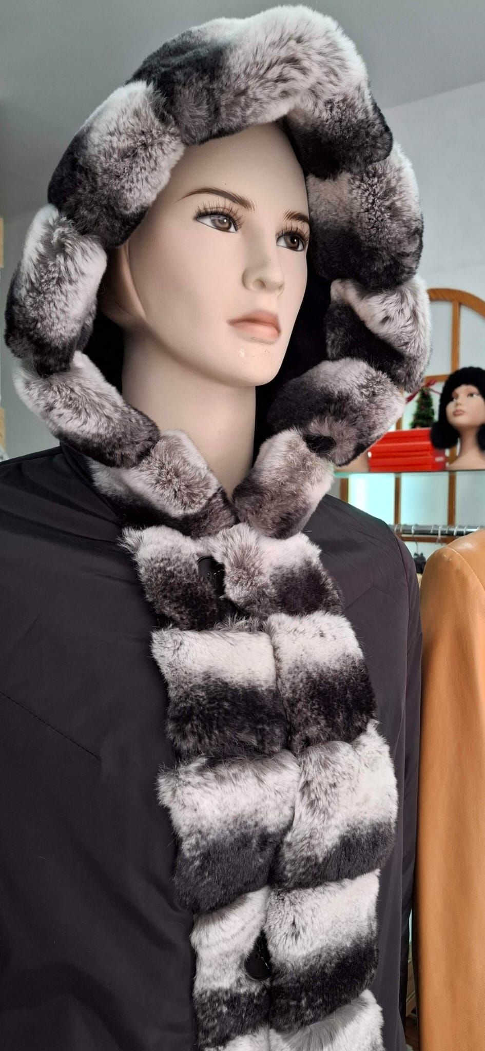 Maniquí con capucha y bufanda peluda en color negro, blanco y gris.
