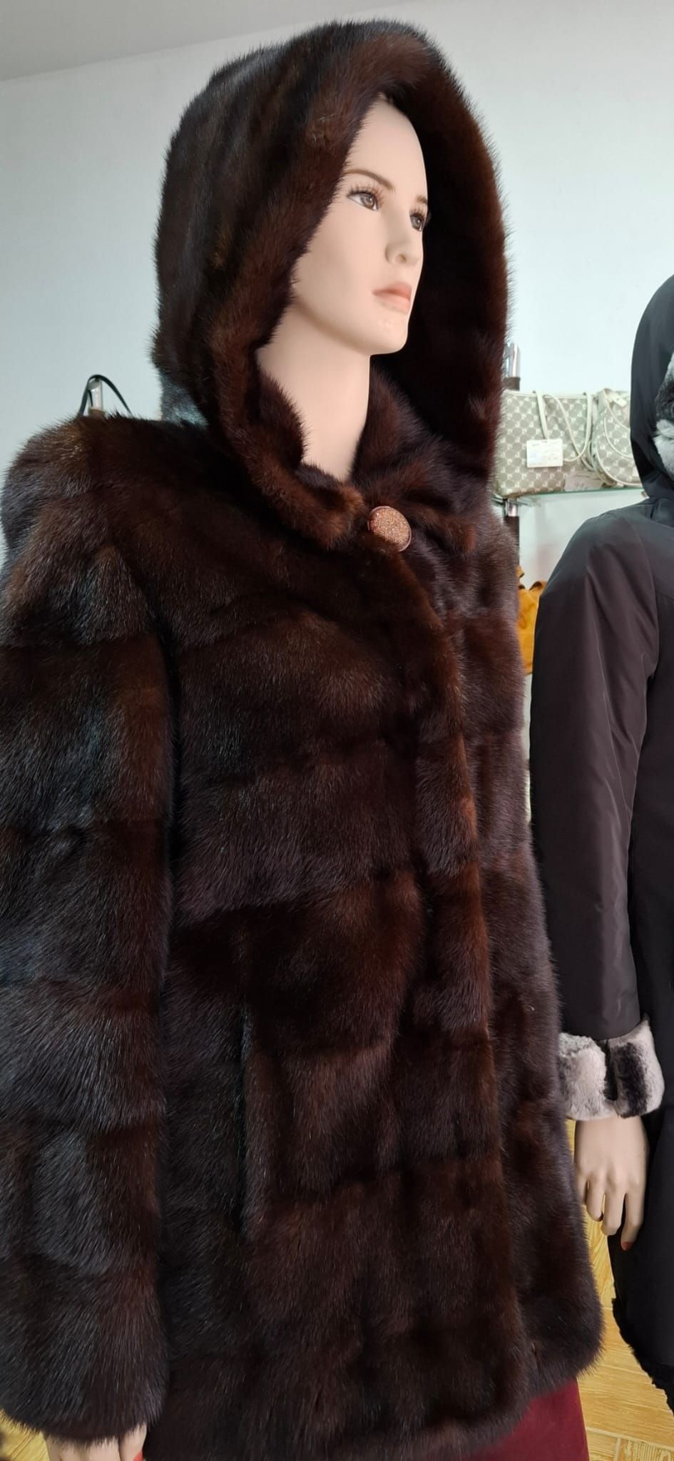 Maniquí con abrigo de piel de color marrón oscuro y capucha.