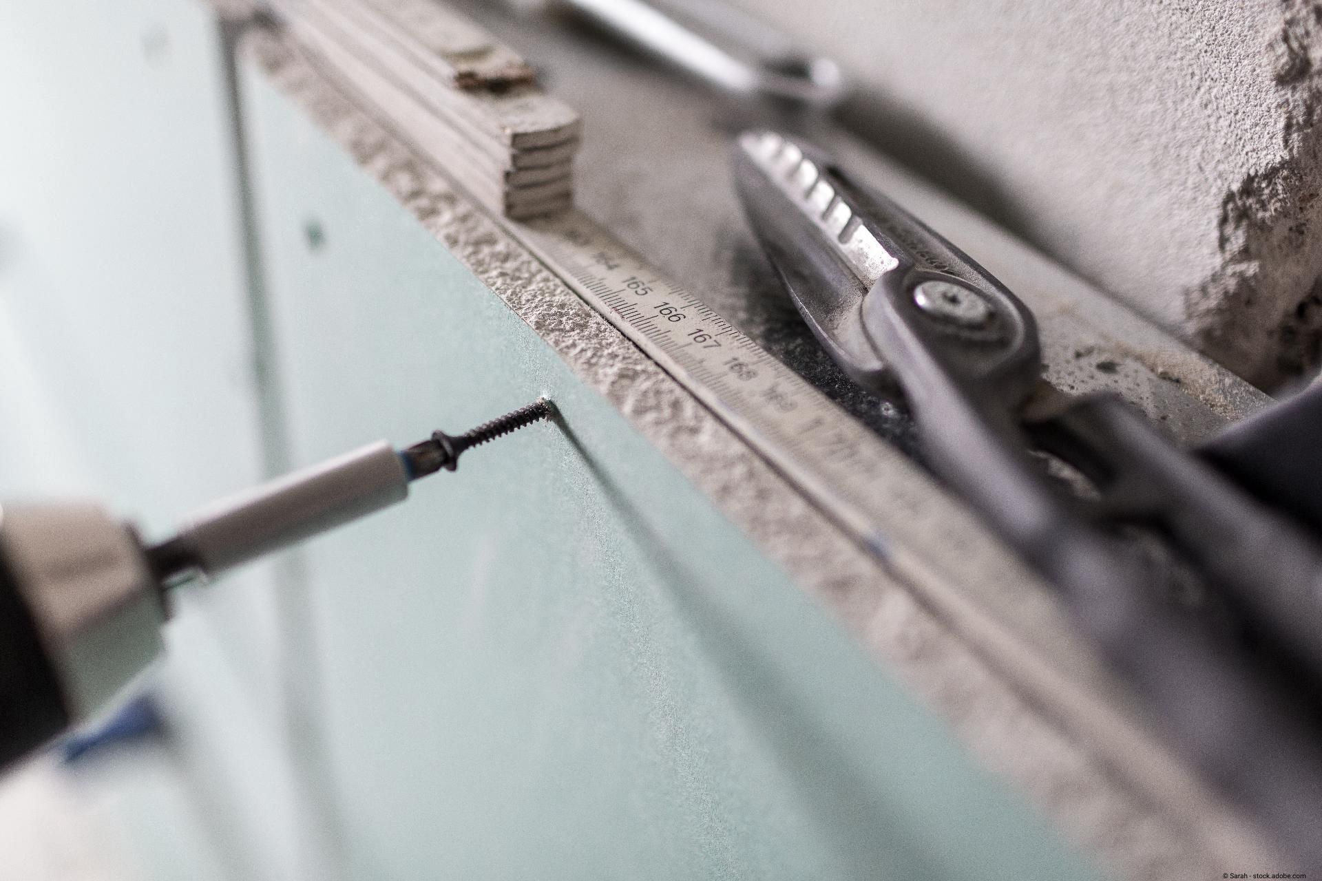 Schrauben und Werkzeug beim Trockenbau an einer Gipskartonwand