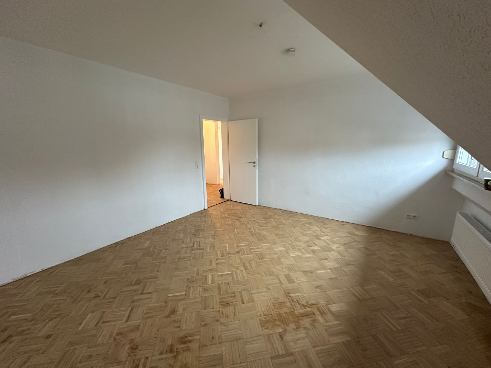 Frisch gestrichener Wohnraum mit Parkettboden und weißer Wandfarbe