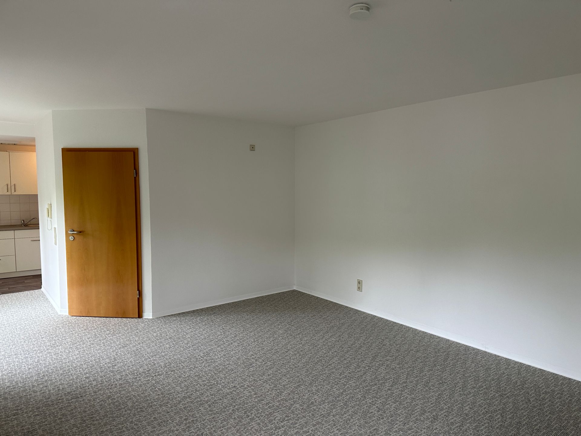 Renovierter Wohnraum mit hellem Teppich und weißen Wänden