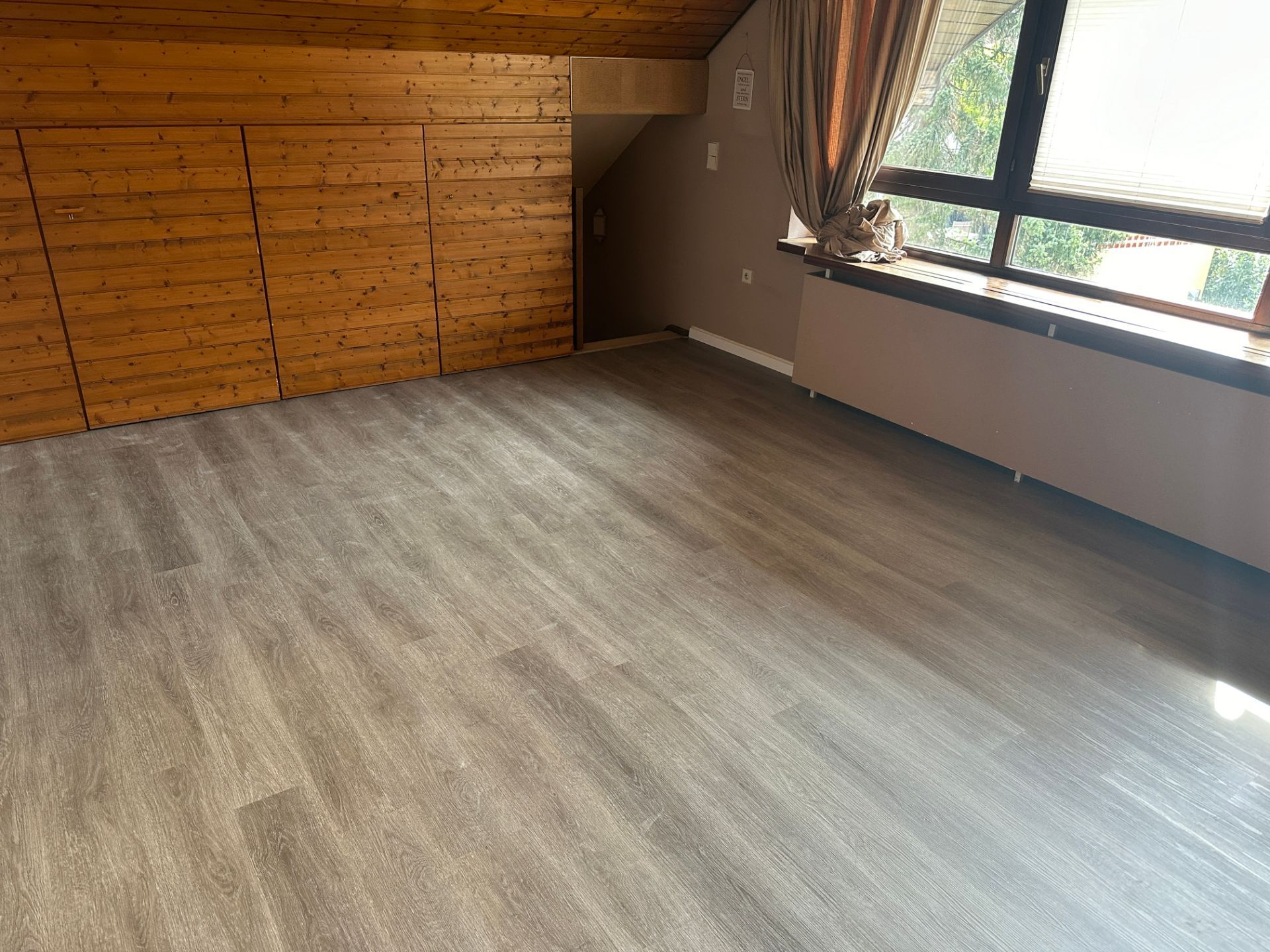 Fertiggestelltes Dachzimmer mit Holzdecke und neuem Boden