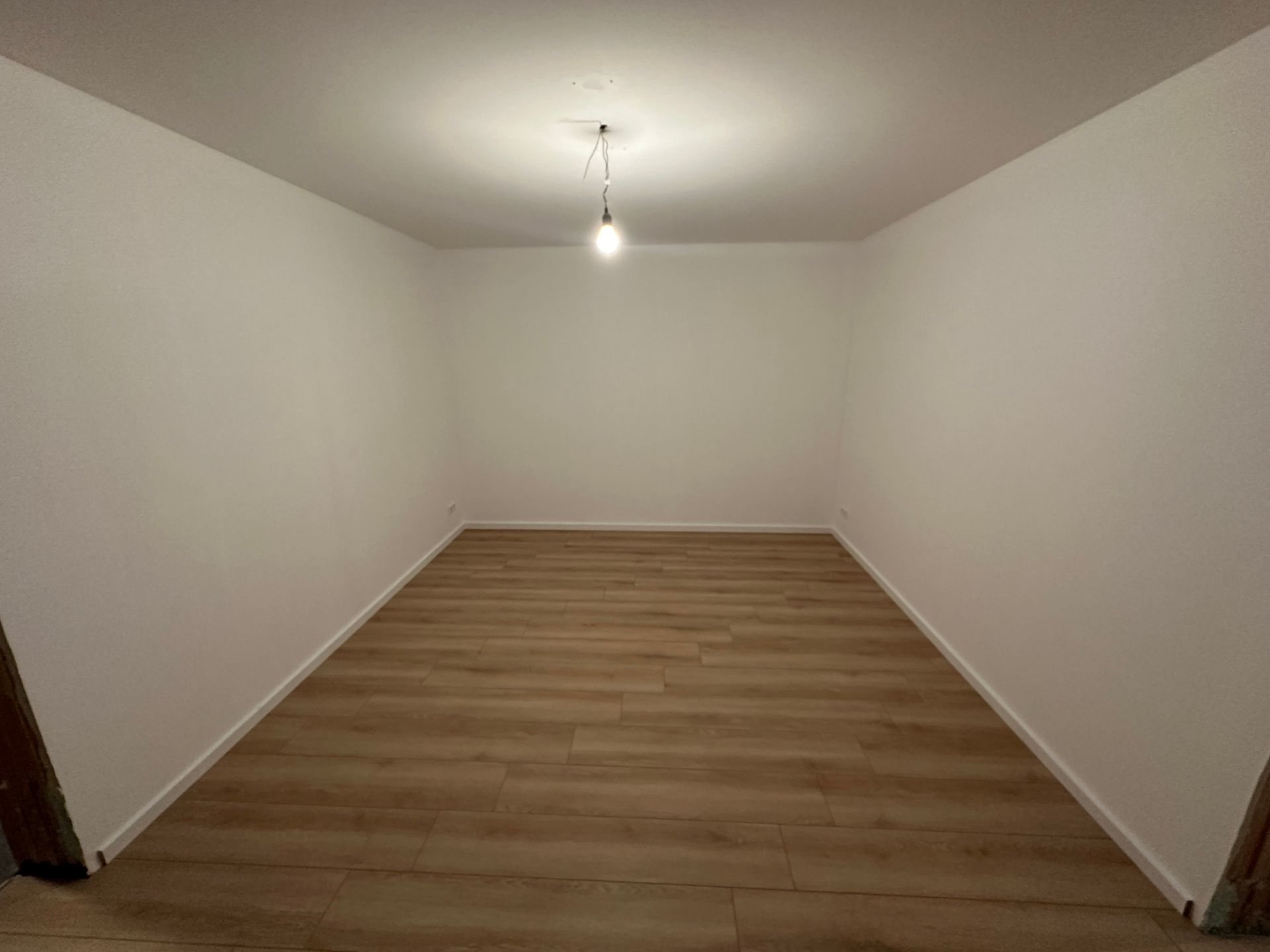 Frisch renoviertes Zimmer mit hellem Holzoptikboden