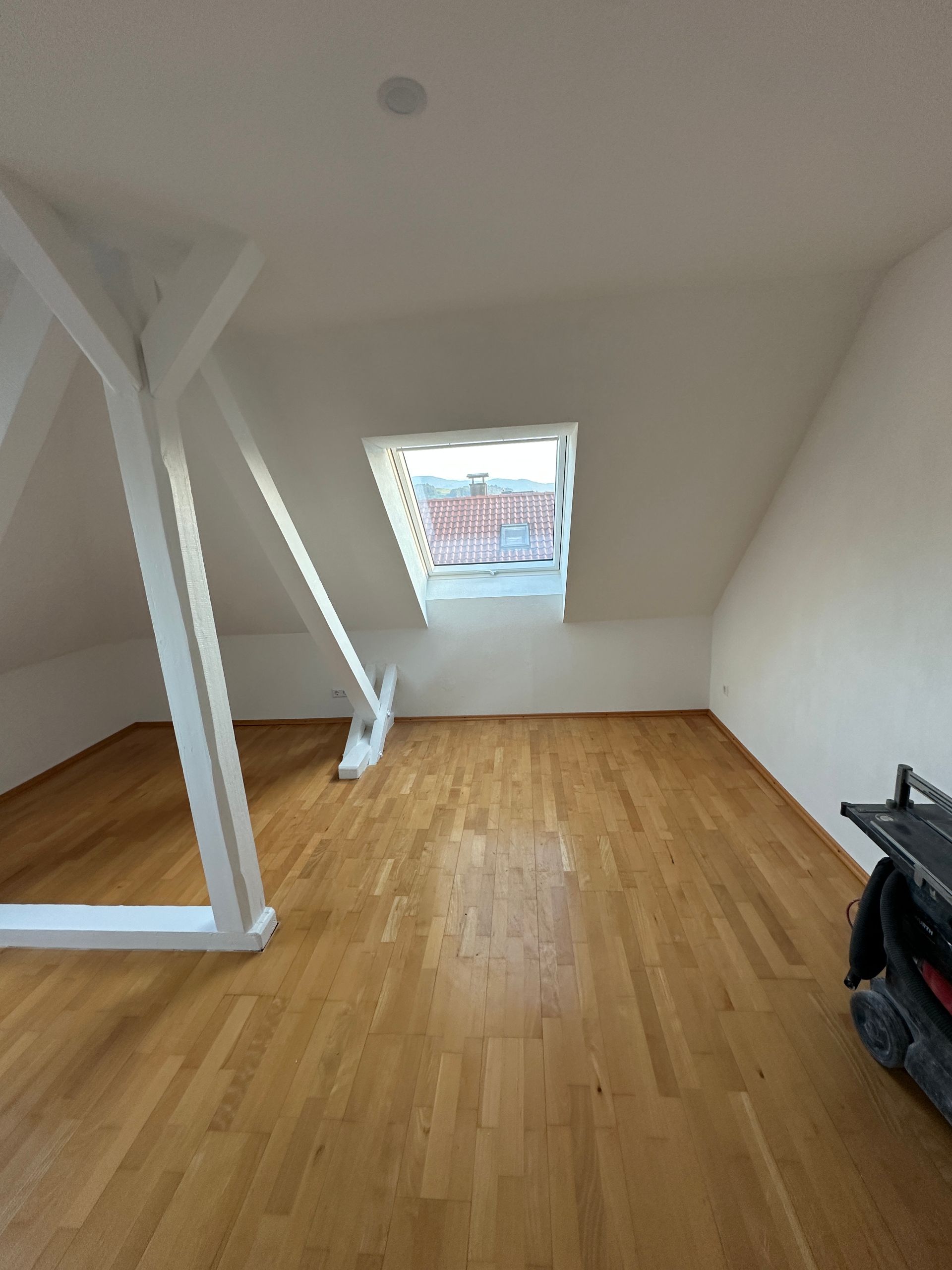 Fertiggestelltes Zimmer mit Parkettboden und weißen Wänden