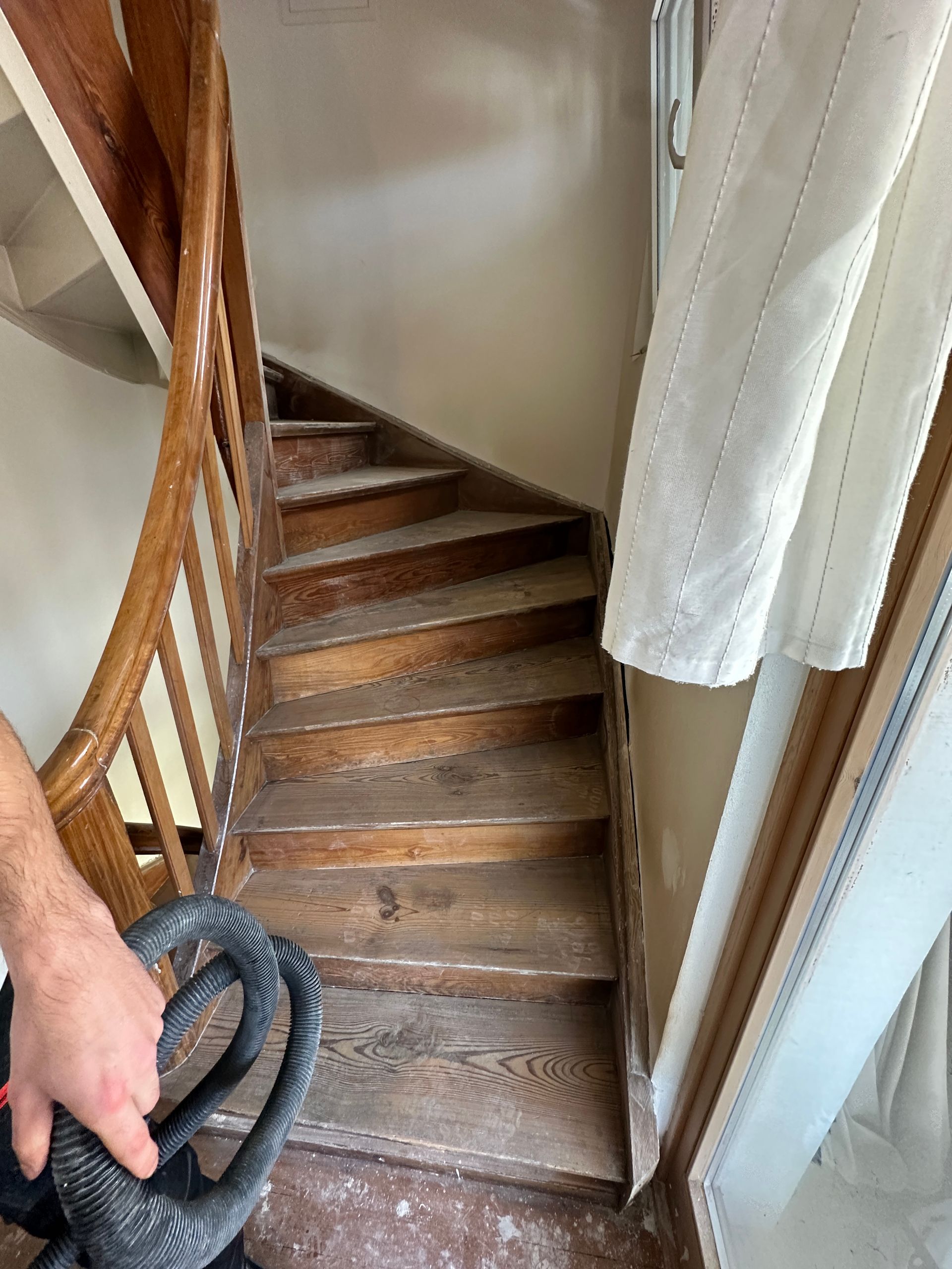 Treppenaufgang mit Holzgeländer im sanierten Innenbereich