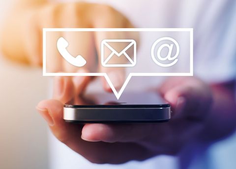 Une personne qui tient le portable avec des pictogrammes de contact dans une bulle de discussion.